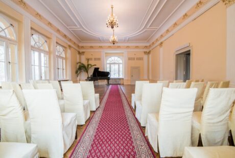 Krzesła ustawione dla publiczności na sali balowej. W tle fortepian.