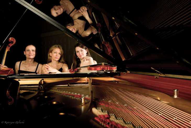Trzy kobiety siedzą za otwartym fortepianem.